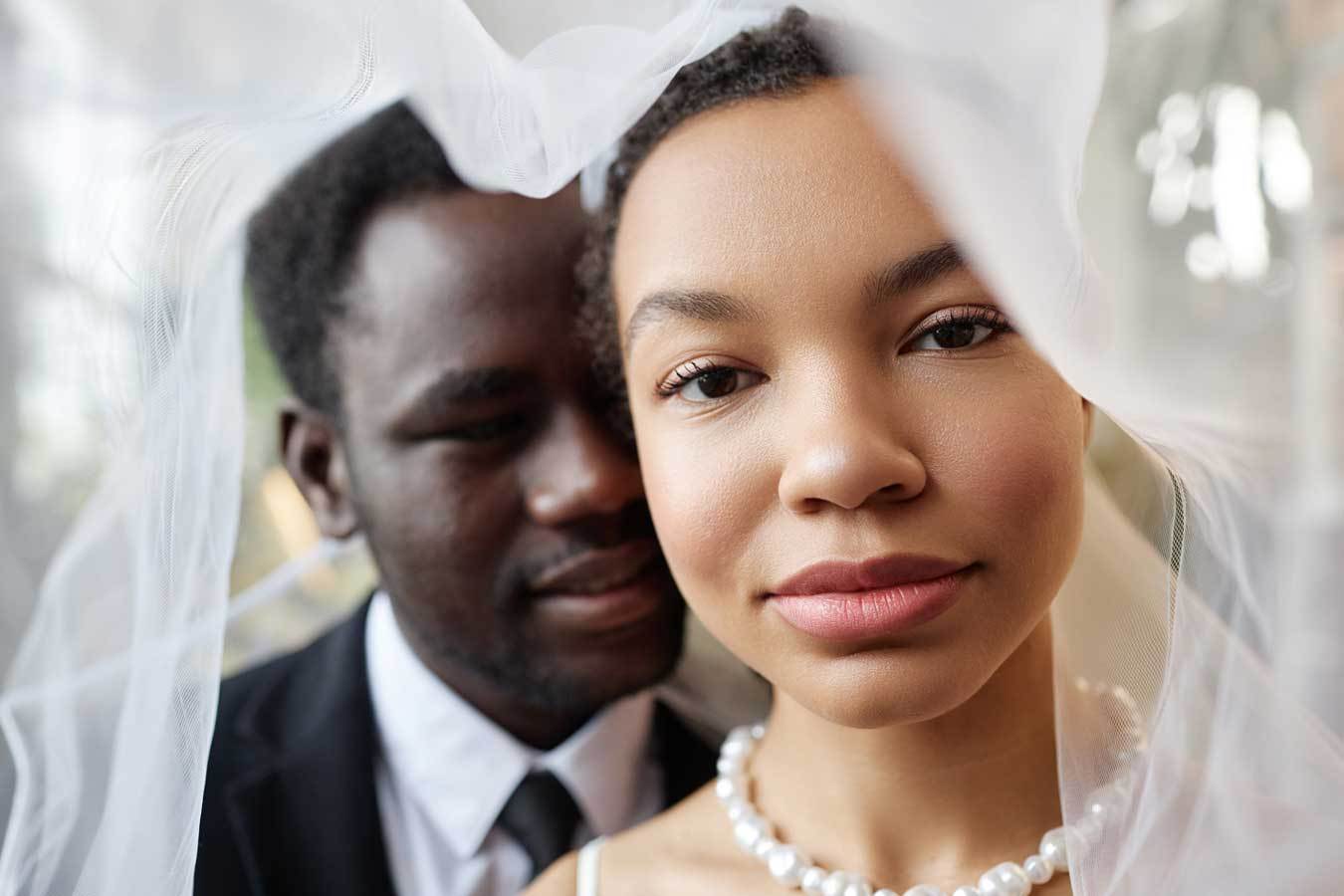 Closeup black couple as bride and groom looking at camera under veil