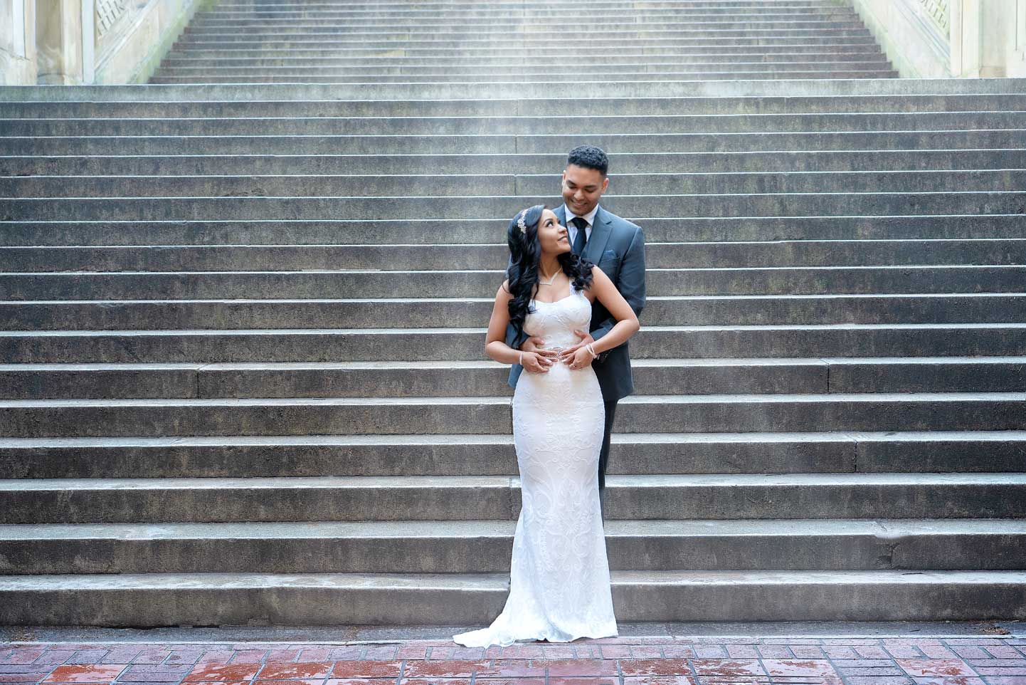 Couple celebrating their wedding at NYC City Hall steps, holding bouquet and smiling.